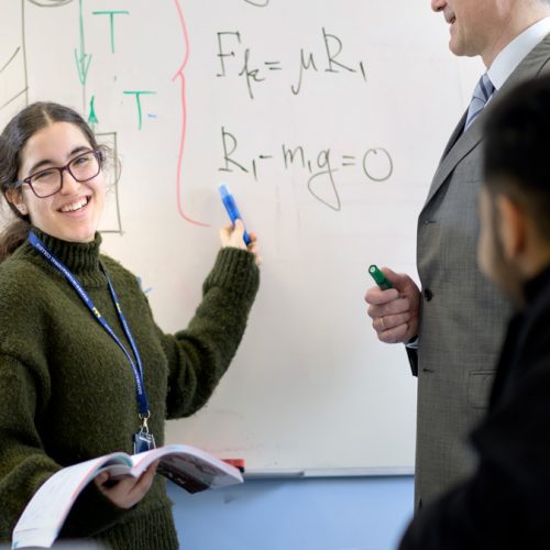 Student working out mathematical calculations at the board